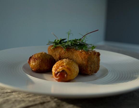 En tallerken med sprød grøntsagsfritters toppet med friske urter og små bagte kartofler.