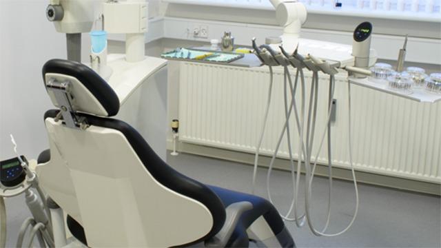 Et tandlægekontor med en tandlægestol, udstyr og instrumenter til tandbehandling.