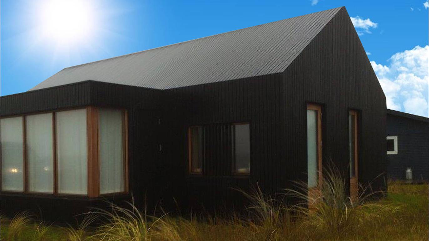Et moderne sort hus med store vinduer, omgivet af græs og under en klar blå himmel.