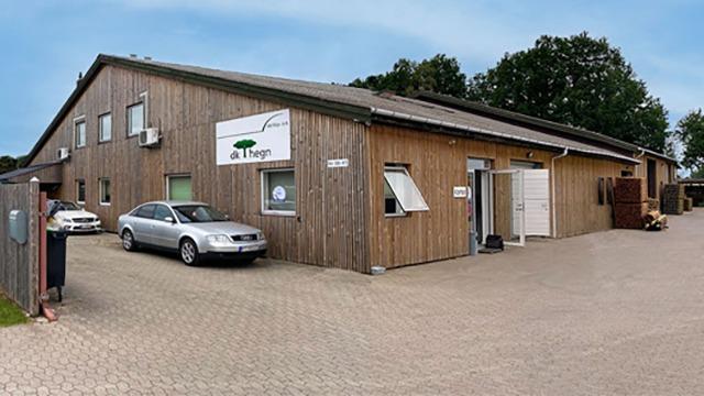 En træbygning med en stor facade, biler parkeret foran og et skilt med navnet "Thyges".