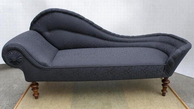 En elegant, mørkeblå chaiselong med bølgende design og træben.
