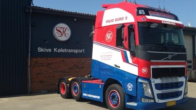 En farverig Volvo lastbil parkeret foran Skive Kolestransport bygning.