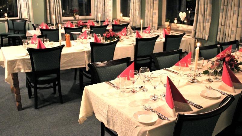 En elegant restaurant med dækkede borde, røde servietter og stearinlys i en hyggelig atmosfære.