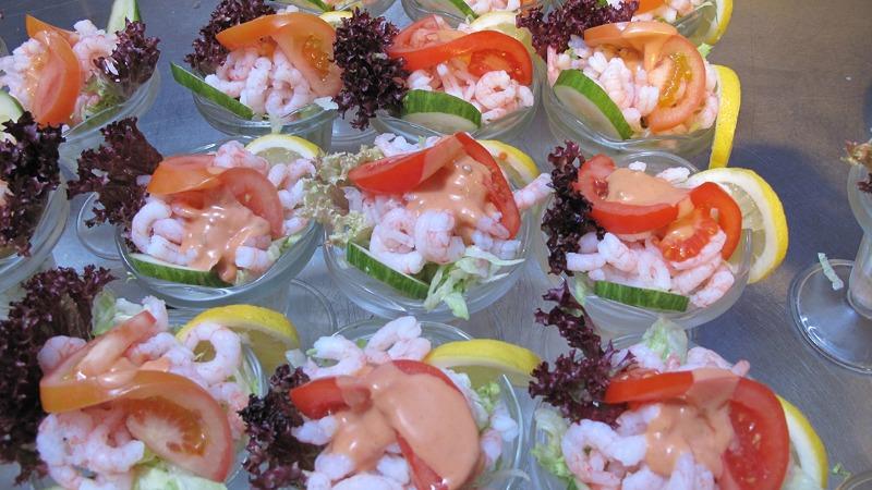 Friske rejesalater i glas med salat, agurk, tomat og citronskiver, pyntet med rød salat.