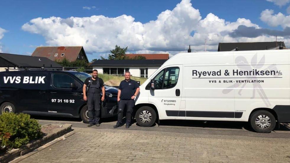 To personer står ved siden af to varevogne med logoer fra VVS Blik og Ryevad & Henriksen.