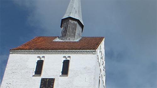 Et gammelt hvidt kirketårn med spids tag og ur, beliggende under en blå himmel.
