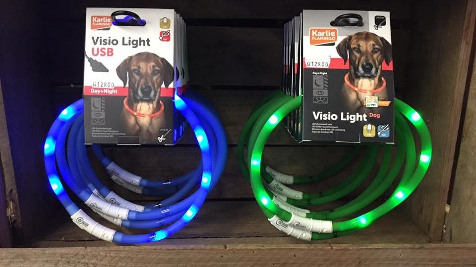 To hundehalsbånd med LED-lys i blå og grøn farve, præsenteret i en trækasse.