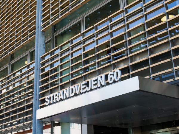 Facade af bygning med skiltet "STRANDVEJEN 60" og moderne trælameller.
