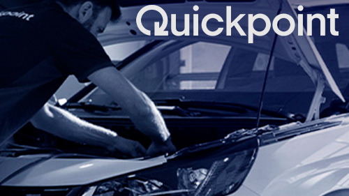 Mekaniker arbejder på motoren i en bil hos Quickpoint, med fokus på reparation og vedligeholdelse.