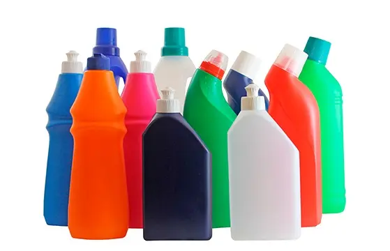 Farverige rengøringsmidler i plastflasker arrangeret i en gruppe på hvid baggrund.