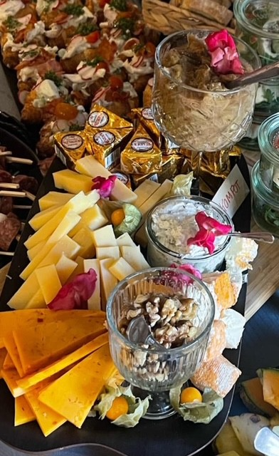 En lækker tapas-anretning med forskellige oste, nødder, brød og delikate dips prydet med blomster.