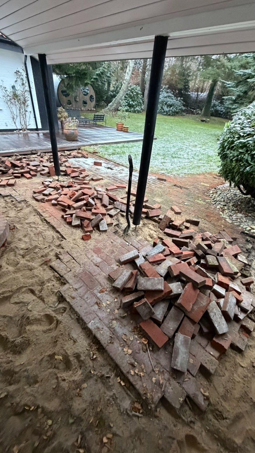 Bunker af mursten ligger på en sandet overflade under en terrasse med sne i haven.