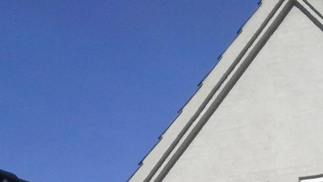 Et hus med en grå væg og en klar blå himmel i baggrunden.