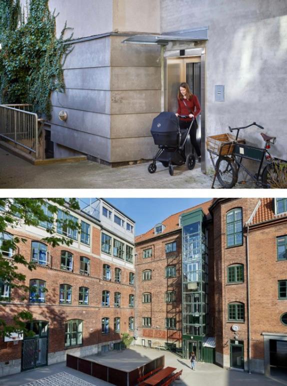 En kvinde med en barnevogn går ud af en elevator ved en moderne bygning med gårdhave og cykelparkering.