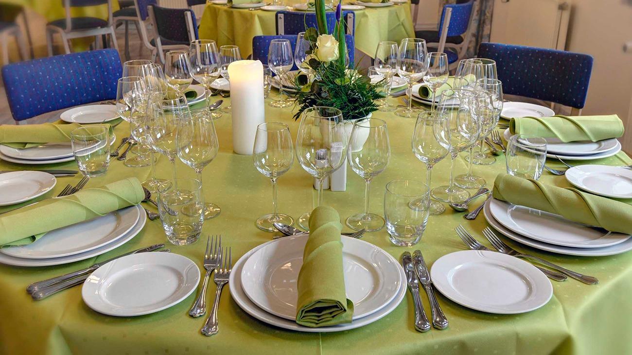 Et elegant dækket bord med grønne servietter, glas og tallerkener, klar til festligheder.