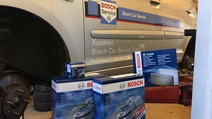 Billede af en Bosch bilservice med kasser af reservedele og en informationsplakat i værkstedet.