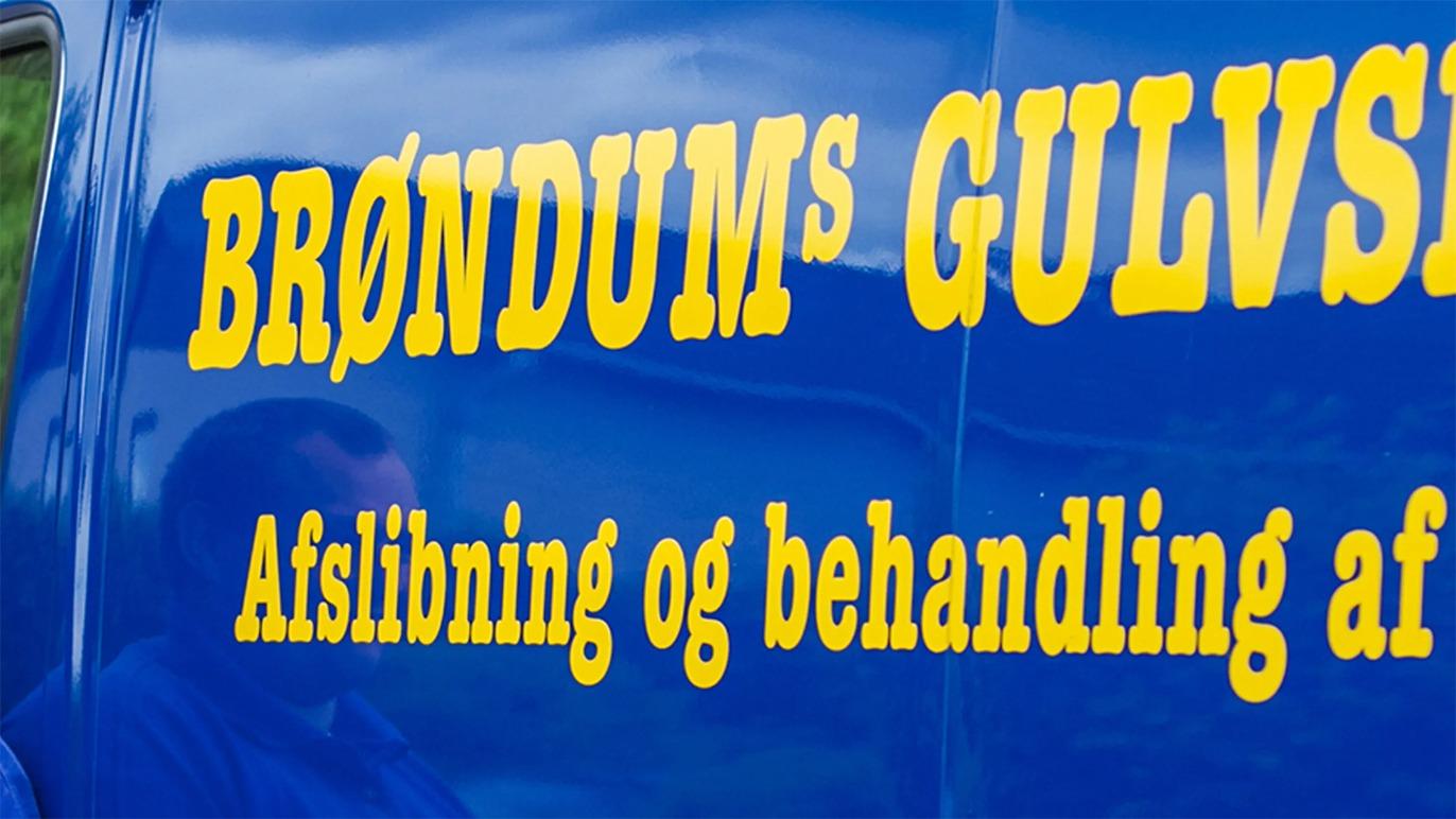 Brøndums Gulvservice bil med tekst om afslibning og behandling af gulve i gule bogstaver på blå baggrund.
