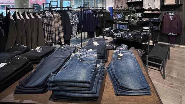 Butik med tøj, herunder jeans og skjorter, præsenteret på hylder og borde.