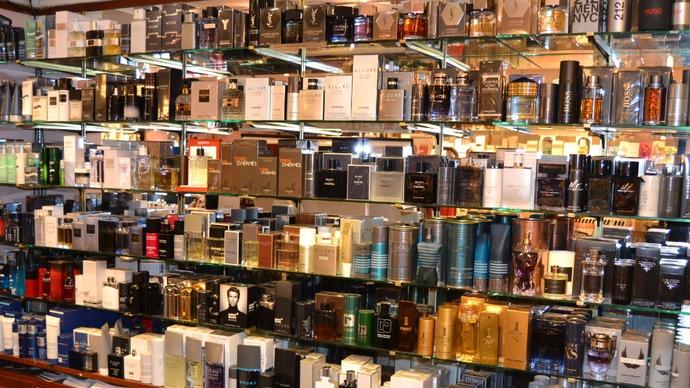Et udvalg af parfumer i en butik, præsenteret på hylder med forskellige mærker og emballager.