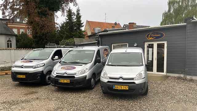 Tre Citroën varevogne parkeret foran en grå bygning med logo og vinduer.