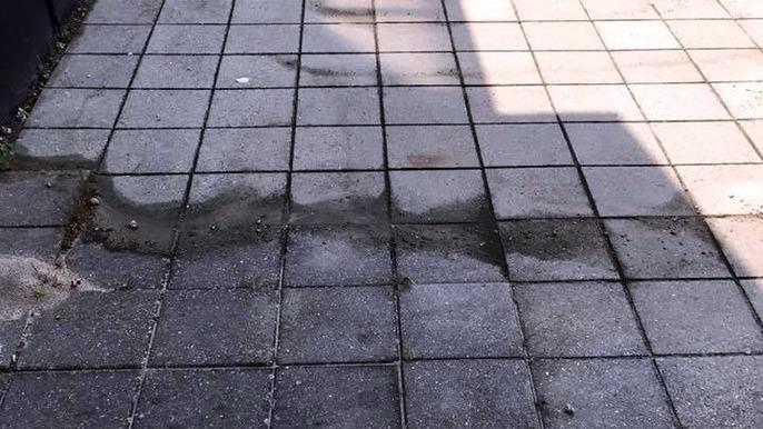 Våd flisebelægning med spor af vand og mudder, der strækker sig over flere fliser.