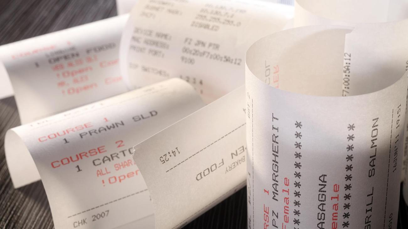 Kvitteringer fra restaurantbesøg, der viser forskellige retter og priser, ligger på et bord.
