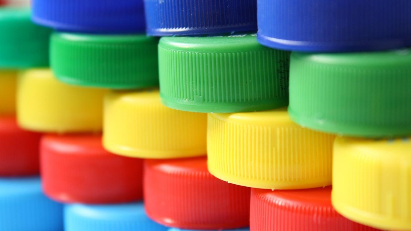 Farverige plastikkapsler stablet i en kreativ struktur med blå, grønne, gule og røde farver.