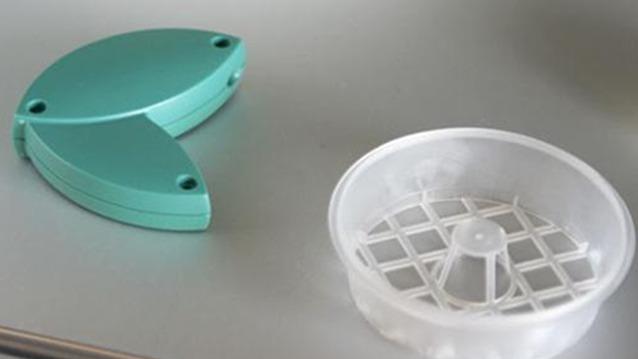 Grøn plastikdel og gennemsigtig skål med gittermønster til madlavning eller opbevaring.