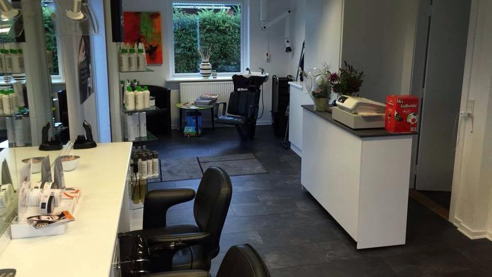 Frisørsalon med moderne indretning, stole, reception og produkter på hylderne.