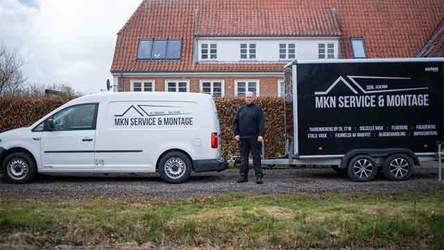 En mand står ved siden af en hvid varevogn og en sort trailer med MKN Service & Montage logo.