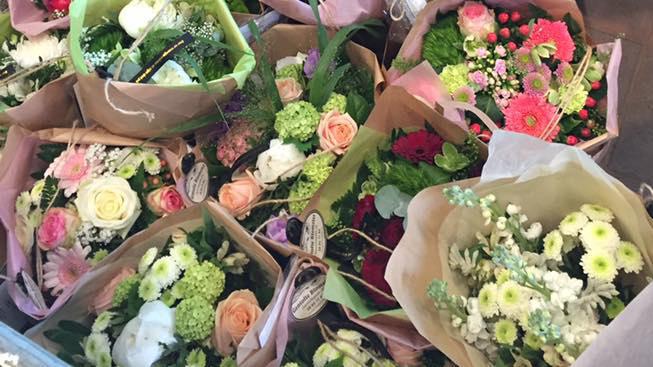 Smukke buketter med farverige blomster i papirindpakning, arrangeret i en kasse.