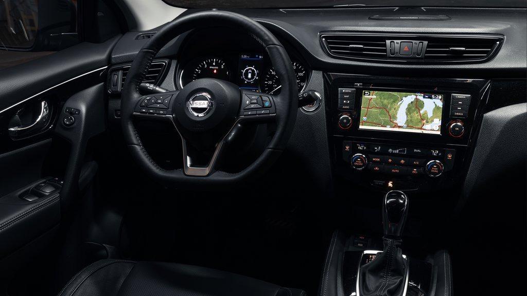 Interiør af en Nissan bil med moderne instrumentbræt, navigationssystem og læderbetræk.