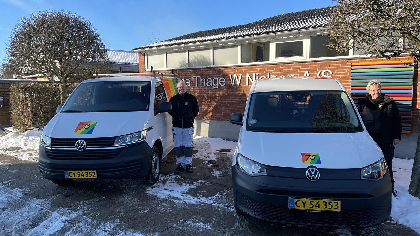 To personer står ved siden af to Volkswagen varevogne foran bygningen med skiltet "Tage W. Nielsen A/S".