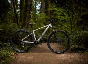 En mountainbike står på en grusvej omgivet af grønne træer og buske i en skov.