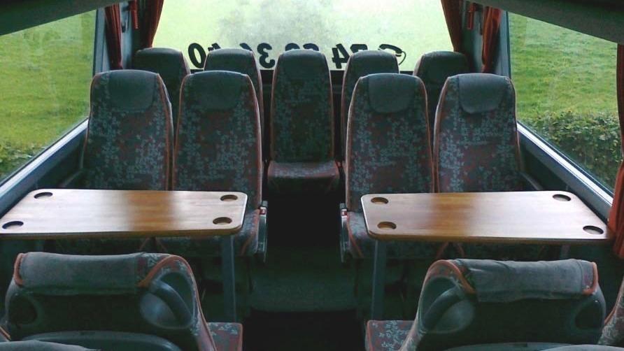 Indvendig udsigt af en bus med komfortable sæder og borde tilpasset til grupper.