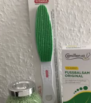 Grøn fodfil fra Titania hængende på væggen ved siden af en krukke og en pakke fodbalsam.
