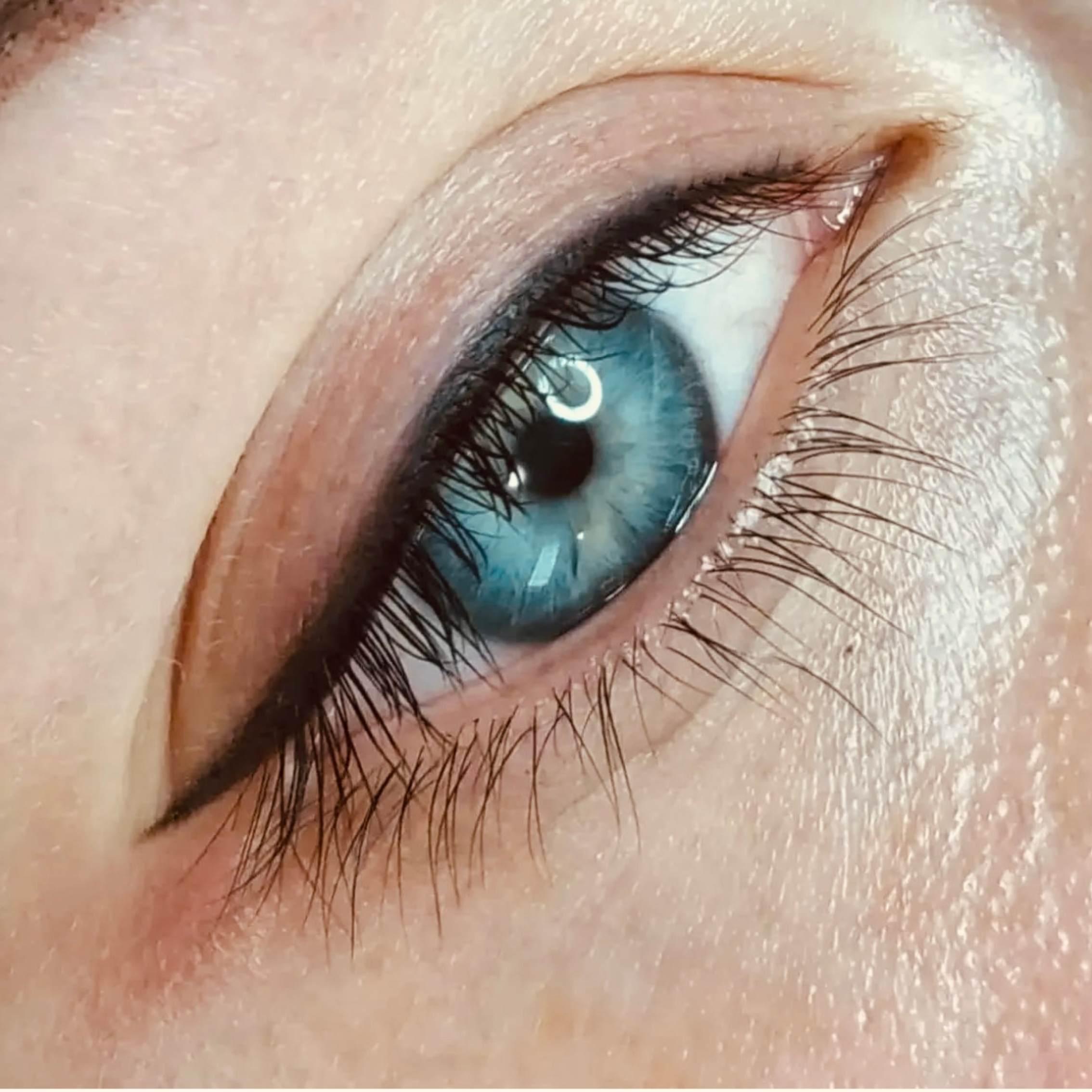 Nærbillede af et blåt øje med eyeliner og lange vipper, der fremhæver øjets farve og detaljer.