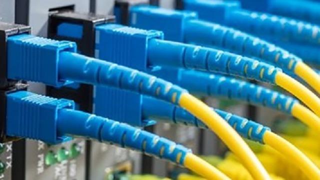 Blå fiberoptiske kabler med gule ledninger tilsluttet en netværksrouter.