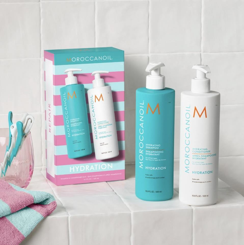 To sæt Moroccanoil hydreringsprodukter i en farverig emballage, placeret på en flisebelagt overflade.