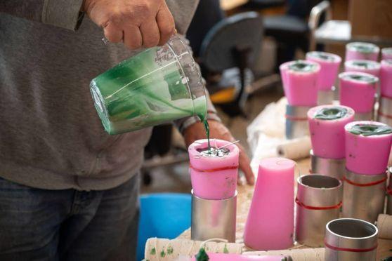 En person hælder grøn maling i en pink form, mens der er flere farvede former i baggrunden.