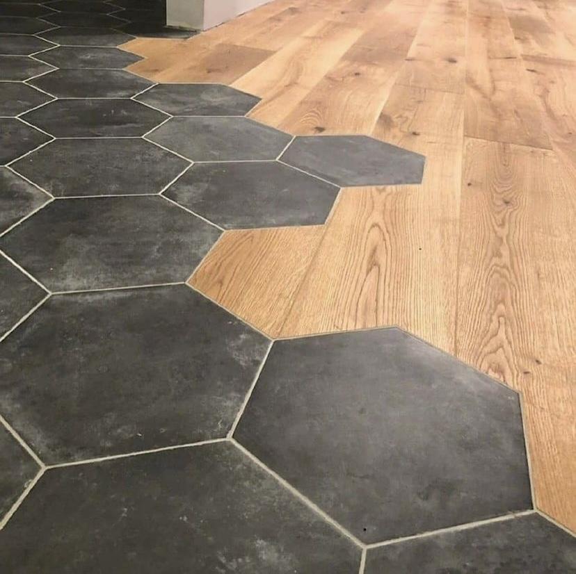 Gulv med hexagonale fliser og lyst trægulv, der skaber en moderne og stilfuld overgang mellem materialerne.