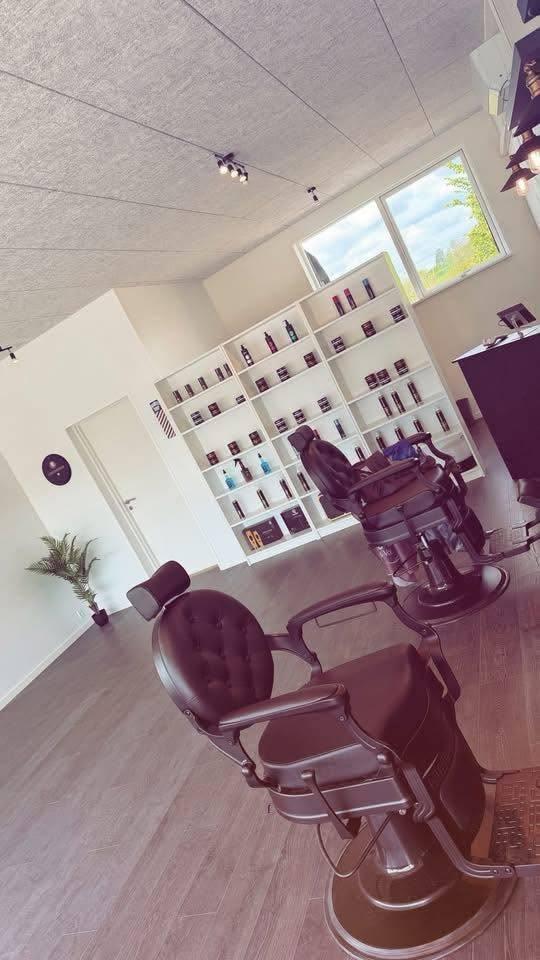 En moderne frisørsalon med en barberstol i forgrunden og hylder med hårprodukter i baggrunden.