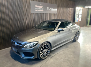 En grå Mercedes cabriolet parkeret i et moderne bilhus med trævægge.