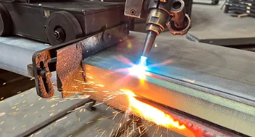 Svejsebrænderen smelter metal med gnister og flammer på en stålplade i et værksted.